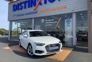 Audi A4 Avant blanc vue 3/4 avant droit, stationnée devant un showroom Distinxion avec logo visible.