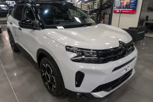 Citroën C5 Aircross hybride blanc Okénite avec toit noir, vue 3/4 avant en intérieur showroom.