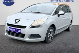 Peugeot 5008 gris vue 3/4 avant droit, montrant la calandre et les phares allumés sur fond neutre.