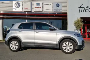 Profil côté gauche d'un Volkswagen T-Cross 1.0 TSI 95 Lounge argent métal, compact et moderne, sur fond de concession.