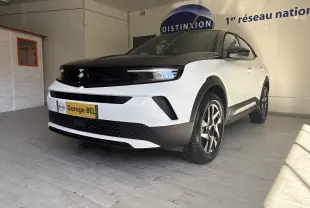 Opel Mokka blanc Arktis en 3/4 avant droit, avec calandre noire et jantes alliage 17 pouces, en intérieur showroom.