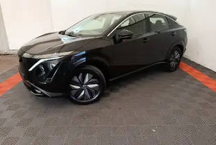 Nissan Ariya 63kWh noir en 3/4 avant droit, avec jantes modernes et lignes fluides dans un espace intérieur.