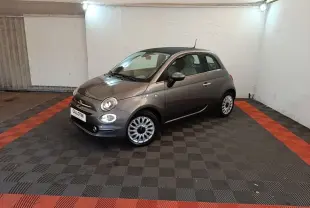Vue 3/4 avant droite d'une Fiat 500 gris foncé stationnée sur un sol à damiers noir et rouge dans un garage.