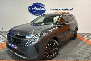 Peugeot 5008 gris titane en 3/4 avant droit, avec jantes noires et phares LED allumés, en showroom.