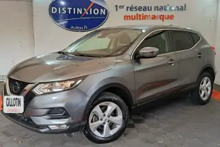 Nissan Qashqai gris clair vu de 3/4 avant droit, avec jantes alliage et phares allumés en intérieur showroom.