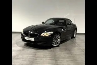 BMW Z4 Roadster noir vue 3/4 avant droit, phares allumés et jantes alliage dans un intérieur neutre.