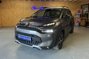 Citroën C3 Aircross gris platinium métal vue 3/4 avant droit avec toit blanc et jantes bi-ton en intérieur showroom.