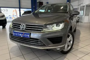 Volkswagen Touareg gris foncé vu de 3/4 avant droit avec phares LED allumés en showroom.