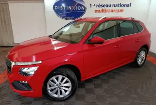 Vue 3/4 avant gauche d'un Skoda Kamiq rouge 2024 avec jantes alliage et barres de toit argentées.