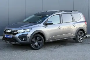 Vue 3/4 avant droite du Dacia Jogger gris schiste avec barres de toit et jantes noires distinctives.