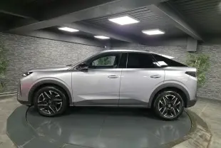 Vue de profil côté gauche d’un Peugeot 3008 gris métallisé avec jantes alliage noires et toit noir dans un showroom.