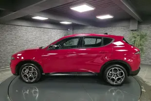 Vue de profil côté gauche d'un Alfa Romeo Tonale rouge avec jantes en alliage et détails noirs brillants.
