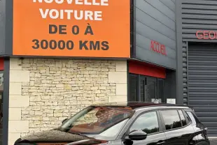 Jeep Avenger noir vue 3/4 avant droit, SUV compact avec calandre distinctive et jantes modernes, devant un bâtiment commercial.