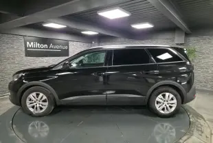 Profil côté gauche d'un Peugeot 5008 noir métallisé 2021 dans un showroom avec jantes alliage 17 pouces.
