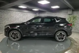 Vue de profil côté gauche d'un CUPRA Formentor noir avec jantes alliage 18'' usinées dans un showroom intérieur.