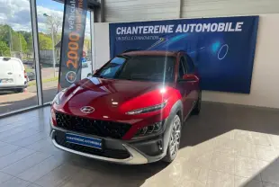 Hyundai Kona Pulse Red Métal vu de 3/4 avant droit dans un showroom avec pare-chocs noir et jantes alu.