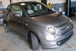 Vue 3/4 avant droit d'une FIAT 500 gris Electroclash avec phares allumés, stationnée en intérieur.