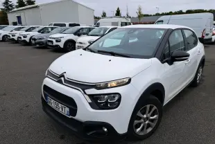 Citroën C3 Société blanche vue en 3/4 avant droit, avec calandre noire et feux LED allumés sur parking.