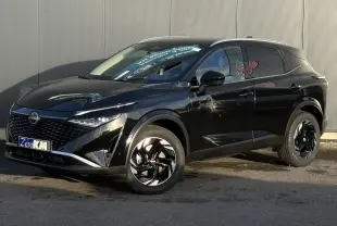Nissan Qashqai noir Kuro en 3/4 avant droit, avec jantes alliage noires et calandre distinctive brillante.