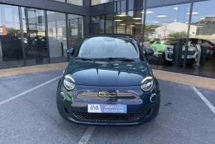 Vue de face d'une FIAT 500C 118 cv icone électrique 2021 en vert foncé métallisé, devant une vitrine de concession.