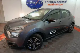 Citroën C3 BlueHDi 100 BVM PLUS gris foncé vue 3/4 avant droit avec protections latérales blanches et jantes stylisées.