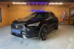 Vue 3/4 avant d'un CUPRA Formentor noir 2022 avec jantes alu et calandre au logo cuivre dans un showroom.