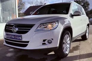 Volkswagen Tiguan blanc vu de 3/4 avant droit avec phares allumés et jantes alliage 17 pouces.