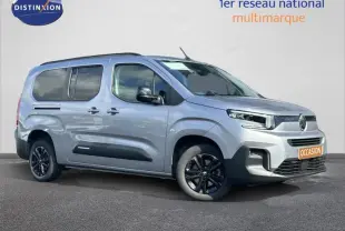 Vue 3/4 avant droite du Citroën Berlingo XL gris Artense avec jantes noires et barres de toit visibles.