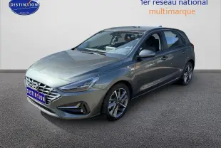 Hyundai i30 gris anthracite vue 3/4 avant droit avec jantes alu et calandre chromée sur fond neutre.