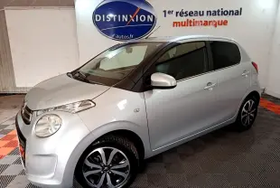 Citroën C1 gris clair vue 3/4 avant droit en intérieur, avec jantes noires et logo Distinxion en arrière-plan.