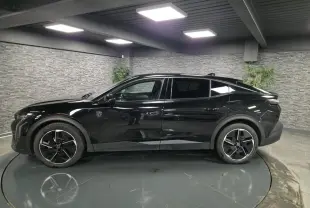 Peugeot 408 hybride noire vue de profil côté gauche, avec jantes alliage 19 pouces et toit plongeant.
