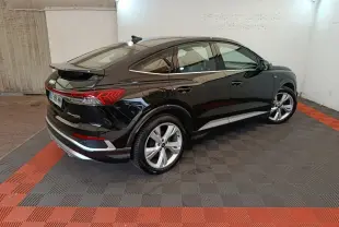 Audi Q4 E-Tron Sportback noir vu en 3/4 arrière droit, mettant en valeur ses feux LED et son design électrique élégant.