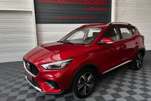 MG ZS rouge 2022 en 3/4 avant droit, avec jantes alliage noires et barres de toit chromées visibles.