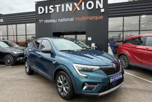 Renault Arkana bleu Zanzibar en 3/4 avant droit, avec jantes alliage et calandre noire distinctive, devant un showroom.