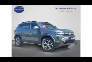 Vue 3/4 avant droite d'un Dacia Duster bleu métallisé avec jantes alu et barres de toit sur fond neutre.