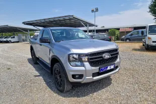 Ford Ranger Super Cabine gris iconic vu en 3/4 avant droit, avec marchepieds et jantes noires sur parking extérieur.
