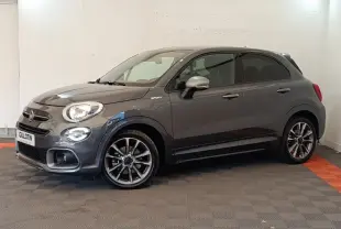 Fiat 500X gris foncé vue de profil droit en intérieur, avec jantes alliage et rétroviseurs argentés.