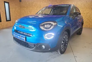 Fiat 500X bleu métallisé vue 3/4 avant droit avec phares LED et jantes alliage noires dans un garage.