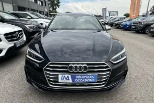 Vue frontale d'une Audi A5 Sportback bleu lunaire métal avec calandre chromée et phares LED allumés.
