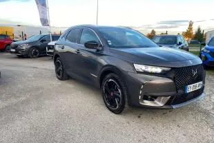 DS7 Crossback gris foncé en 3/4 avant droit, avec calandre noire et jantes noires brillantes sur parking extérieur.