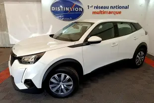 Peugeot 2008 blanc vue 3/4 avant droit, avec phares LED et jantes alliage, sur sol damier intérieur showroom.