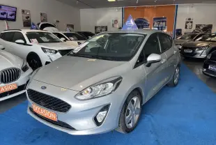 Ford Fiesta gris lunaire métal vue 3/4 avant droit dans un showroom avec plaque orange "OCCASION" visible.