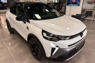 Renault Captur E-Tech blanc nacré toit noir, vue 3/4 avant droit en intérieur avec jantes noires et feux LED distinctifs.