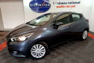 Nissan Micra IG-T 100 Business Edition gris foncé vue de profil droit en intérieur avec phares allumés.