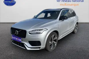 Volvo XC90 gris en 3/4 avant droit avec calandre noire et jantes alu distinctives sur fond neutre.