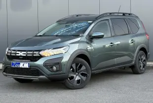 Vue 3/4 avant droit du Dacia Jogger 2024 Vert Cèdre avec barres de toit et jantes noires distinctives.