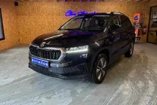 SKODA KAROQ noir 3/4 avant droit en intérieur, avec phares allumés et jantes alliage visibles.
