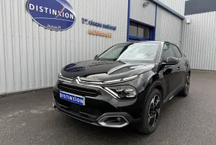 Citroën C4 noire vue 3/4 avant droit, avec calandre distinctive et phares LED modernes, stationnée devant un bâtiment.