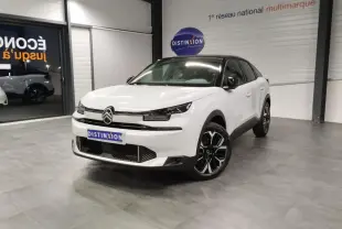 Citroën C4 2025 blanc Okenite avec toit noir, vue 3/4 avant en intérieur showroom, jantes alliage noires et chromées.