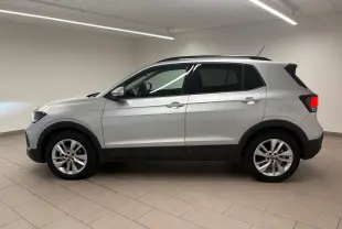 Vue de profil côté gauche d'un Volkswagen T-Cross 2024 en reflet d'argent, avec jantes alliage et vitres surteintées.